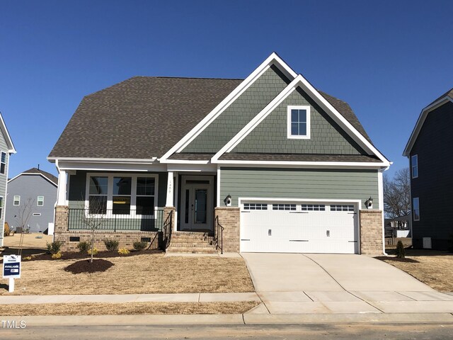 craftsman house with a porch, a shingled roof, brick siding, driveway, and crawl space