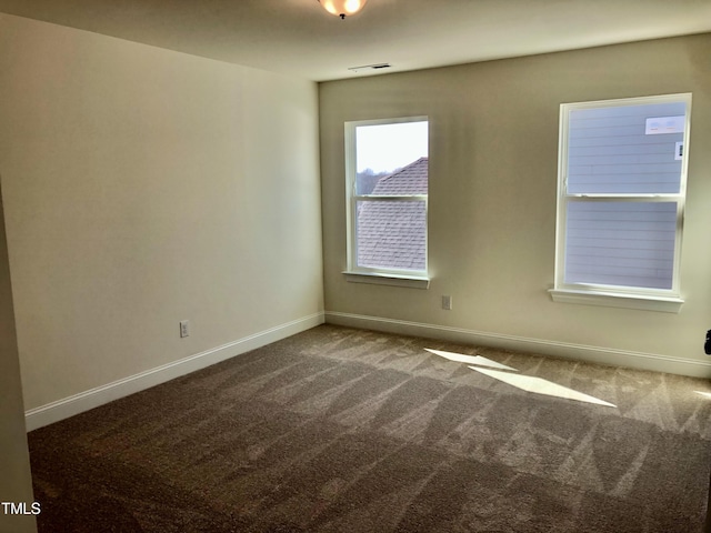 spare room with carpet floors, visible vents, and baseboards