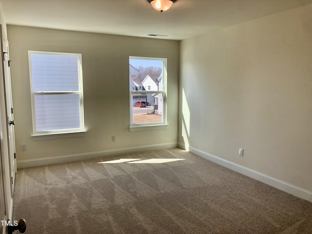 spare room with carpet, visible vents, and baseboards