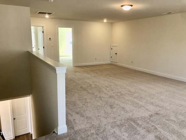 spare room with carpet floors, visible vents, and baseboards