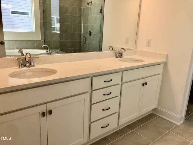 bathroom with double vanity, a stall shower, a sink, and tile patterned floors