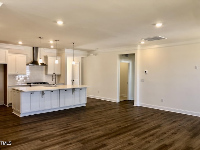 kitchen with visible vents, white cabinets, wall chimney exhaust hood, light countertops, and a sink