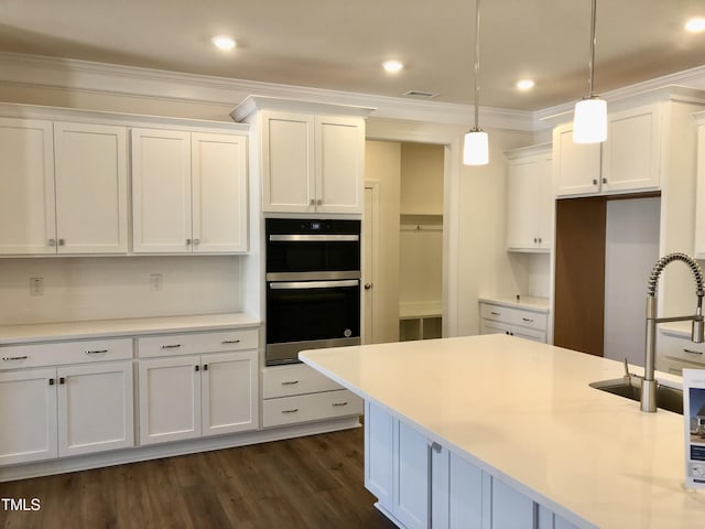 kitchen with dark wood finished floors, white cabinets, dobule oven black, and crown molding