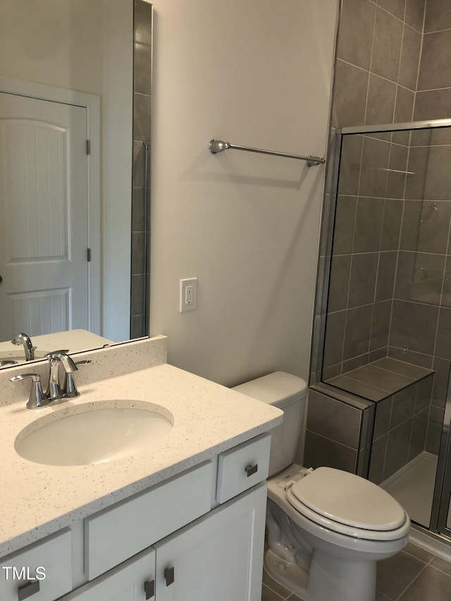 bathroom with vanity, a shower stall, toilet, and tile patterned floors