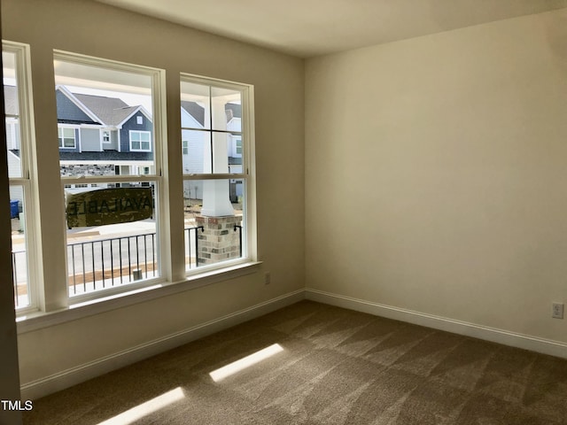 unfurnished room featuring dark colored carpet and baseboards