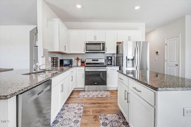 kitchen featuring appliances with stainless steel finishes, sink, light wood-type flooring, backsplash, and white cabinets