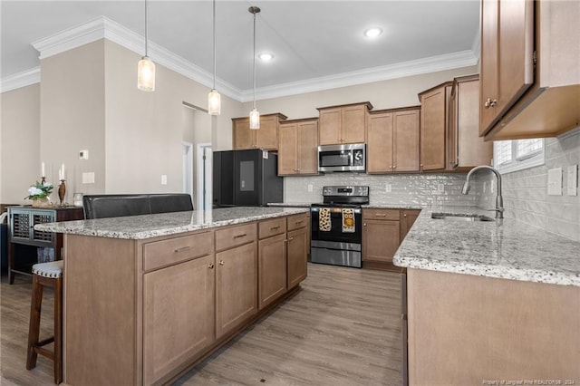 kitchen with a sink, stainless steel appliances, a kitchen breakfast bar, a center island, and crown molding