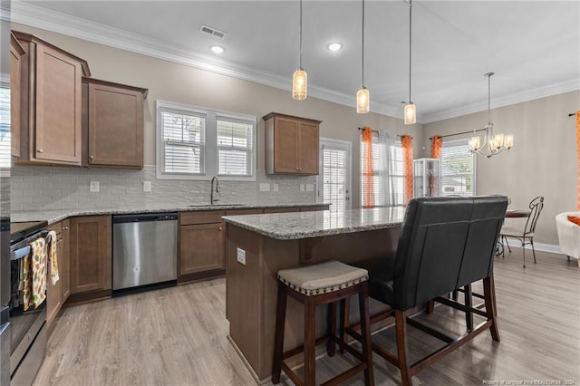 kitchen with decorative backsplash, a sink, a chandelier, stainless steel appliances, and a kitchen bar