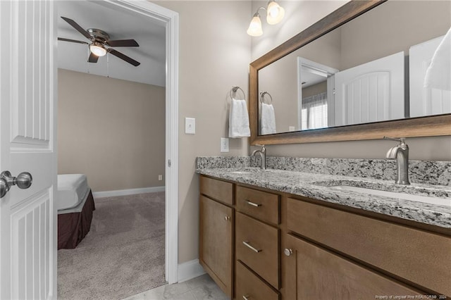 full bathroom featuring double vanity, a sink, ceiling fan, and baseboards