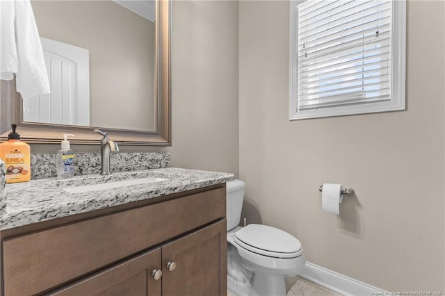 half bathroom featuring baseboards, toilet, and vanity
