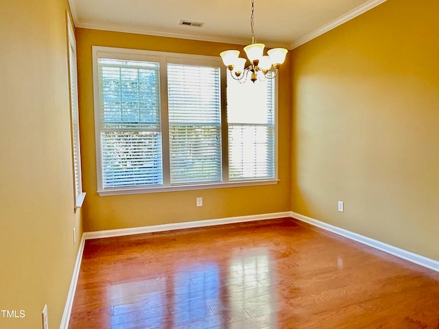 empty room with crown molding, a notable chandelier, and hardwood / wood-style flooring