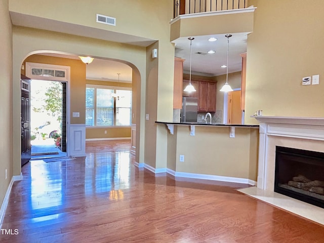 kitchen with a kitchen breakfast bar, hardwood / wood-style flooring, sink, and hanging light fixtures