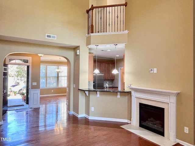 unfurnished living room featuring a towering ceiling, dark hardwood / wood-style floors, and sink