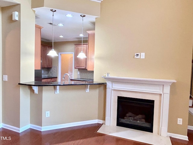 kitchen featuring dark hardwood / wood-style flooring, kitchen peninsula, decorative light fixtures, decorative backsplash, and a breakfast bar