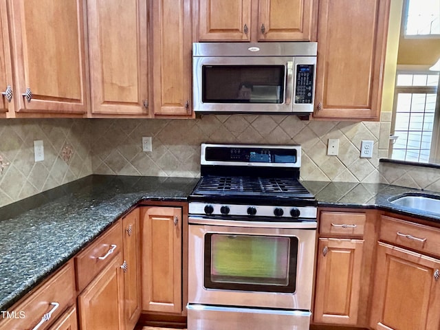 kitchen featuring tasteful backsplash, stainless steel appliances, sink, and dark stone counters