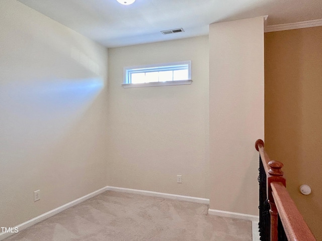 spare room featuring ornamental molding and light colored carpet