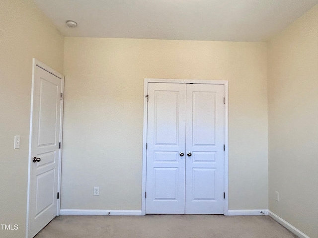 unfurnished bedroom featuring light carpet and a closet