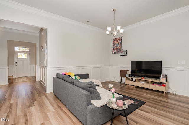 living room with an inviting chandelier, crown molding, and light wood-type flooring