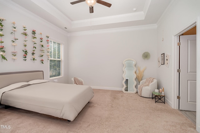 bedroom featuring ornamental molding, a tray ceiling, carpet floors, and ceiling fan