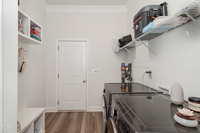 laundry area with wood-type flooring, ornamental molding, and washing machine and clothes dryer