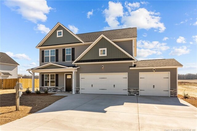 craftsman inspired home with concrete driveway, board and batten siding, fence, a garage, and stone siding