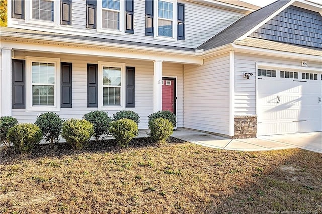 doorway to property with covered porch and a garage