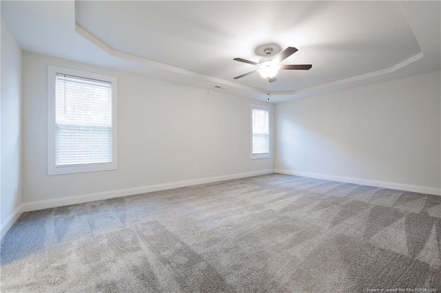 spare room featuring a tray ceiling, carpet floors, and ceiling fan