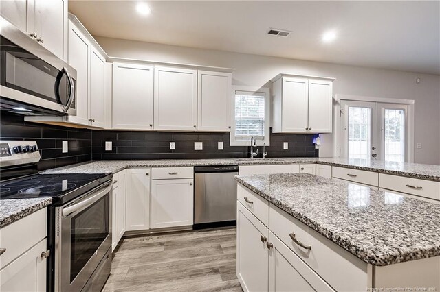 400 Jax Ct, Fayetteville, NC 28312 - kitchen with appliances with stainless steel finishes, light wood-style flooring, a sink, white cabinetry, and tasteful backsplash