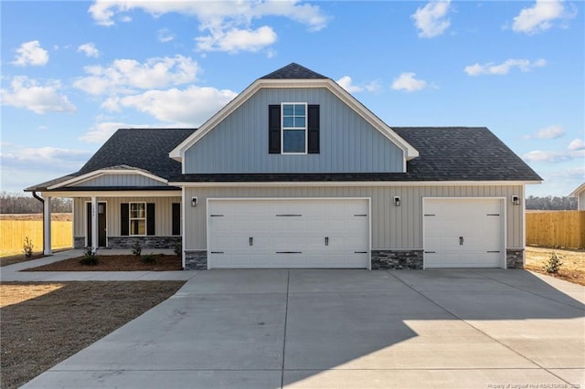 view of front of home with stone siding, roof with shingles, and concrete driveway