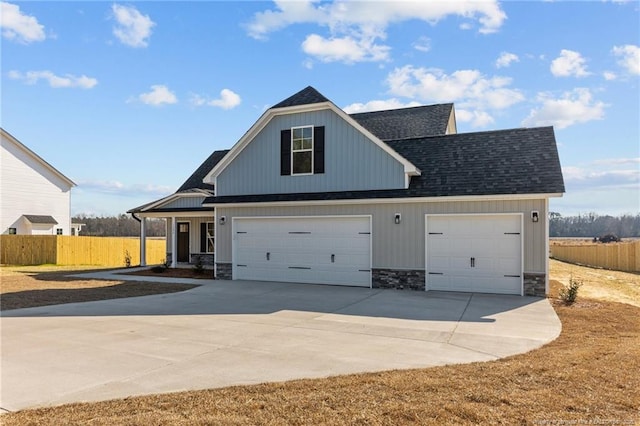 view of front of house featuring driveway, stone siding, a shingled roof, and fence