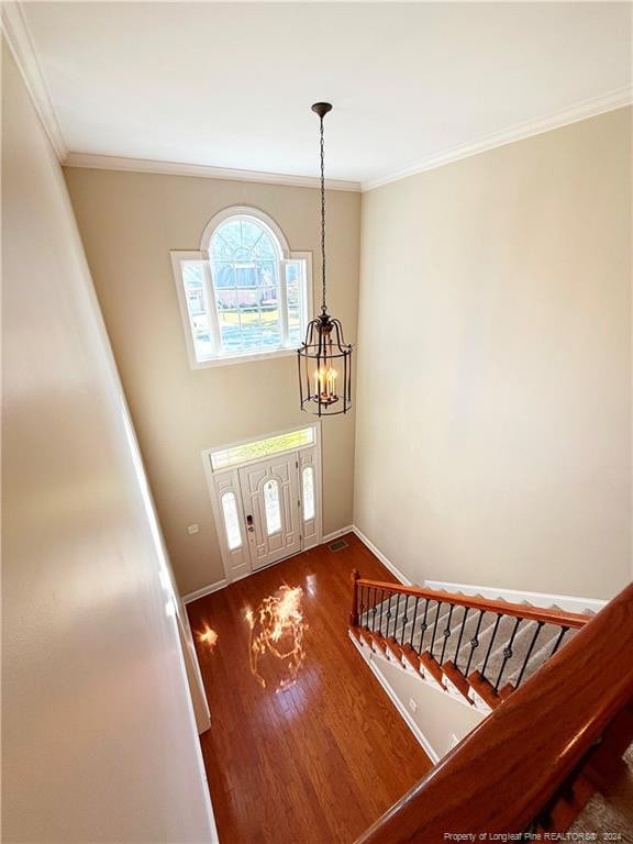 entryway with hardwood / wood-style flooring, an inviting chandelier, and crown molding