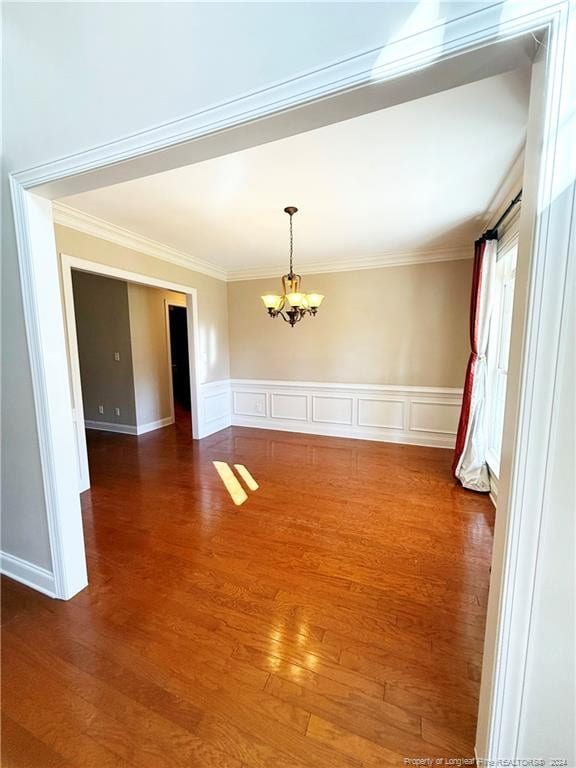 spare room featuring a notable chandelier, dark hardwood / wood-style floors, and ornamental molding