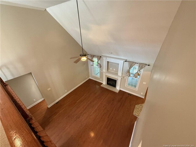 unfurnished living room with ceiling fan, lofted ceiling, and dark wood-type flooring