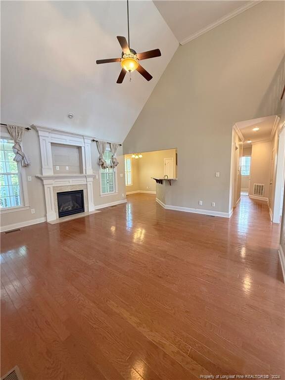 unfurnished living room with hardwood / wood-style flooring, high vaulted ceiling, and ceiling fan