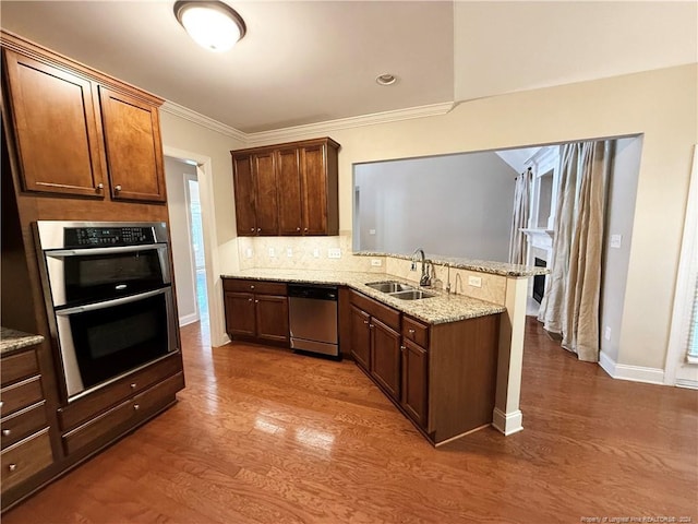 kitchen featuring sink, crown molding, dark hardwood / wood-style floors, kitchen peninsula, and stainless steel appliances