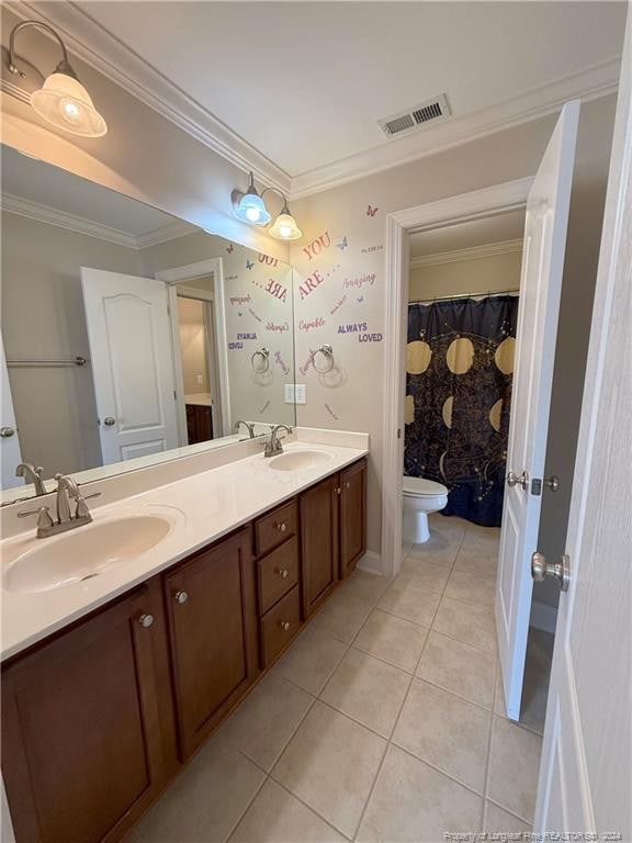 bathroom with tile patterned flooring, vanity, toilet, and crown molding