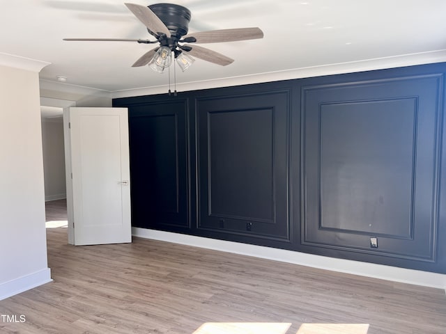interior space featuring a ceiling fan, baseboards, ornamental molding, and light wood finished floors