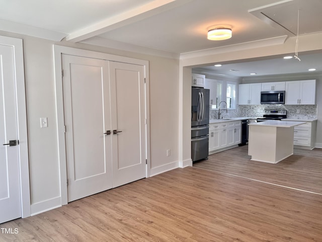 kitchen featuring light countertops, white cabinets, a sink, light wood finished floors, and stainless steel appliances
