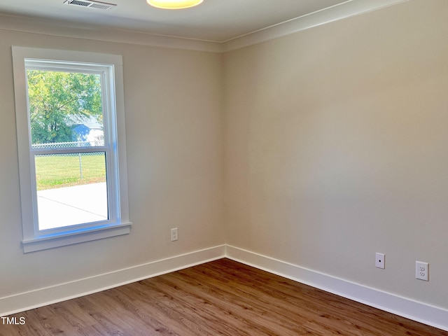 spare room featuring baseboards, wood finished floors, and visible vents