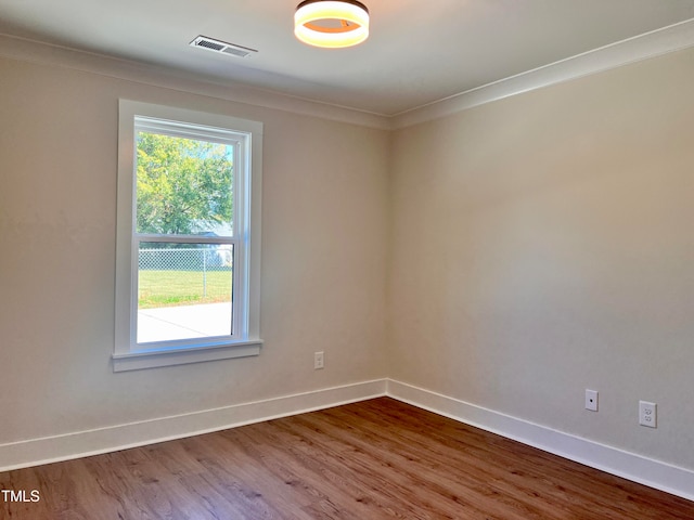 spare room with a wealth of natural light, ornamental molding, and hardwood / wood-style floors