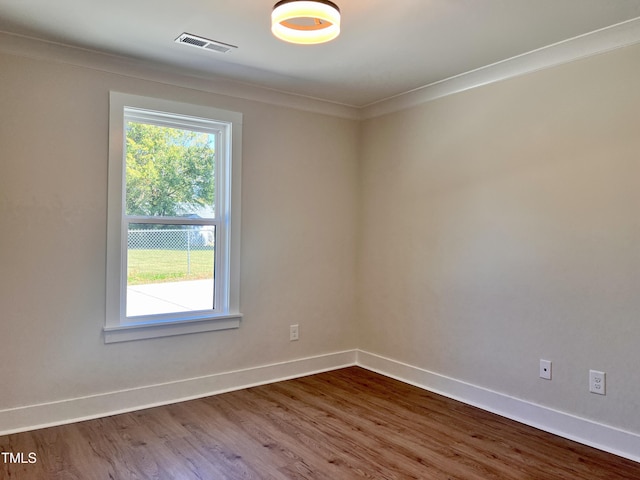 unfurnished room with crown molding, baseboards, wood finished floors, and visible vents