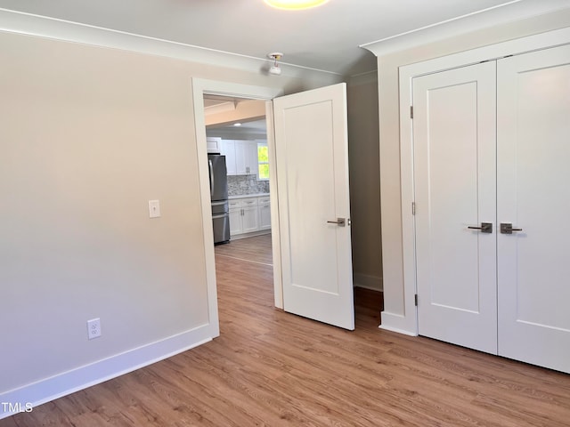 unfurnished bedroom featuring stainless steel refrigerator, a closet, and light wood-type flooring