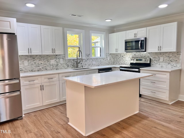 kitchen featuring sink, white cabinetry, light hardwood / wood-style flooring, a kitchen island, and stainless steel appliances