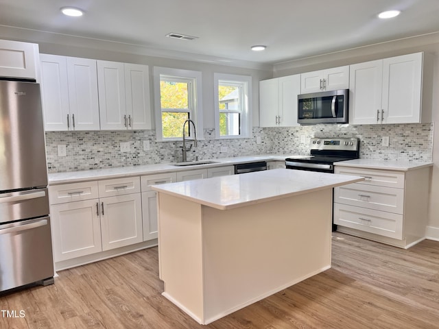 kitchen with stainless steel appliances, visible vents, a sink, and light wood-style flooring