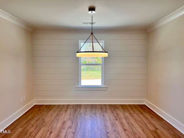 unfurnished dining area featuring ornamental molding and light hardwood / wood-style flooring