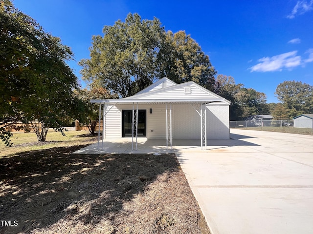 back of property featuring concrete driveway, fence, and a patio area