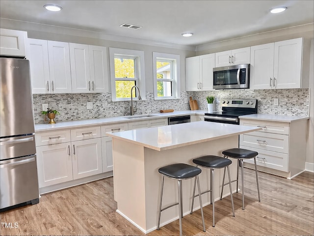 kitchen featuring sink, stainless steel appliances, a center island, and white cabinets