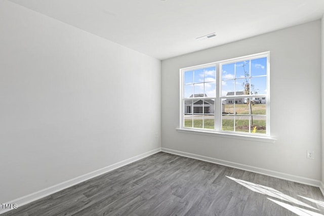 unfurnished room featuring a wealth of natural light and dark hardwood / wood-style floors