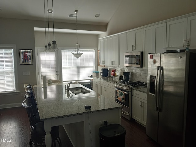 kitchen with a wealth of natural light, light stone counters, stainless steel appliances, and dark hardwood / wood-style flooring