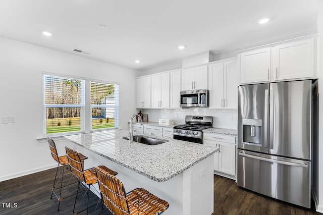 kitchen featuring a kitchen island with sink, appliances with stainless steel finishes, dark wood-style floors, and a sink